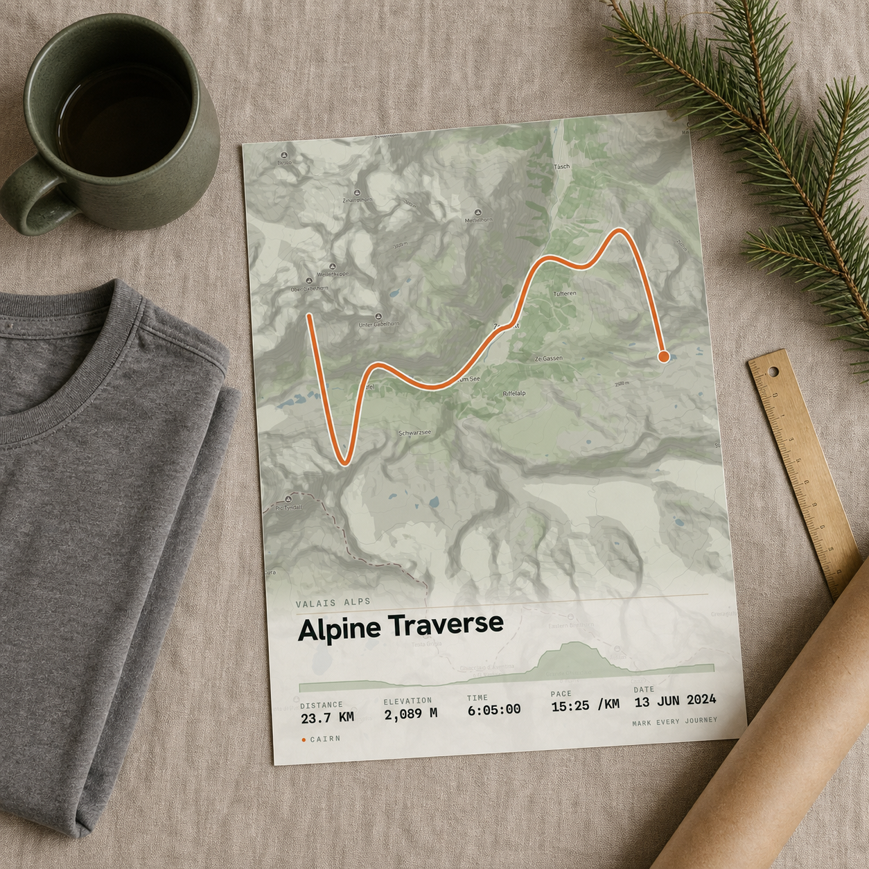 A map-art print, tee, and mug carrying the same real-map route, laid flat on warm linen with a pine sprig and brass ruler